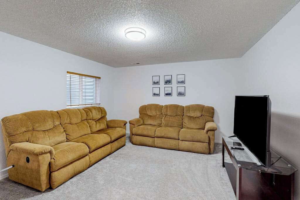 A living room with two sofas, a television, and a window with blinds.