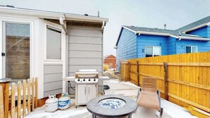 En trädgård med en grill, gastankar, ett bubbelbad och ett staket av trä.