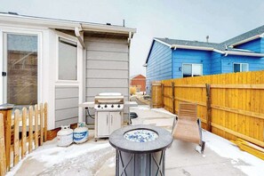 Ein Garten mit Grill, Propangasflaschen, einem Whirlpool und einem Holzzaun.