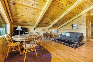 A cozy wooden cabin interior with a dining area, a sofa, and a fireplace. - Waterwheel Retreat - Classic Home • Hot Tub & Cozy Loft (Sturgis)