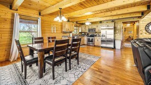 A wooden cabin interior with a dining area, kitchen, and living space. - Waterwheel Retreat - Classic Home • Hot Tub & Cozy Loft (Sturgis)