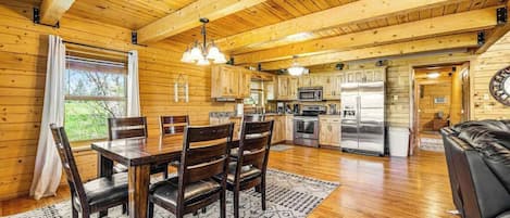 A wooden cabin interior with a dining area, kitchen, and living space.