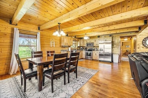 A wooden cabin interior with a dining area, kitchen, and living space. - Waterwheel Retreat - Classic Home • Hot Tub & Cozy Loft (Sturgis)