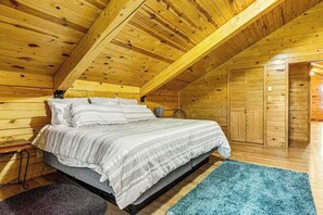 A wooden cabin bedroom with a bed, a blue rug, and a wooden ceiling. - Waterwheel Retreat - Classic Home • Hot Tub & Cozy Loft (Sturgis)