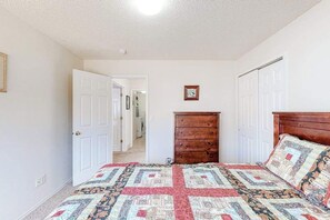 A bedroom with a bed, a dresser, and a door leading to another room. - Windy Hill Retreat - Dog-Friendly Home • Huge Fenced Yard (Colorado Springs)