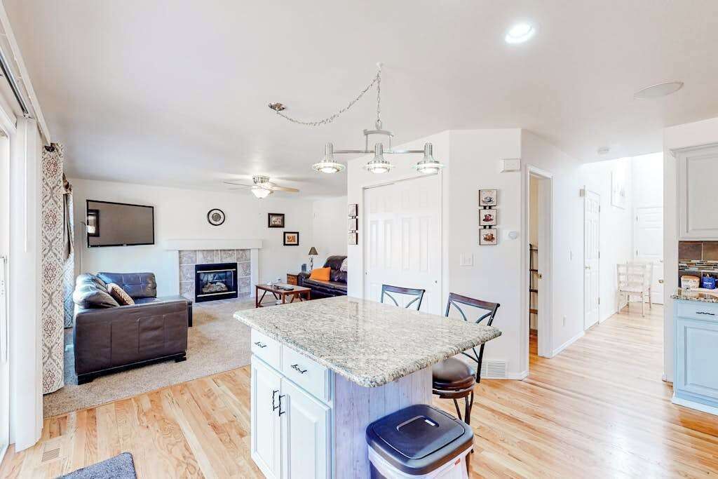 A modern kitchen with granite countertops, a built-in island, and a dining area with chairs.