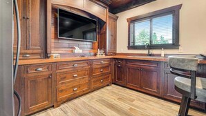A kitchen with wooden cabinets, a built-in oven, and a window with blinds. - Whiskey Ridge Lodge • Hot Tub & Rec Room (Sturgis)