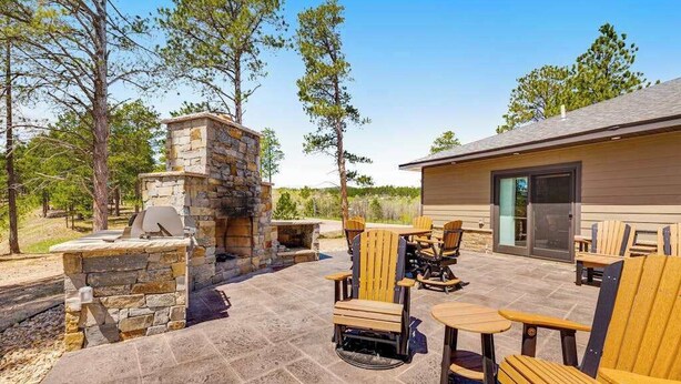 An outdoor patio with stone-built barbecue and seating. - Whiskey Ridge Lodge • Hot Tub & Rec Room (Sturgis)