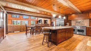 A spacious kitchen with a large island, wooden flooring, and a high ceiling with exposed beams. - Whiskey Ridge Lodge • Hot Tub & Rec Room (Sturgis)
