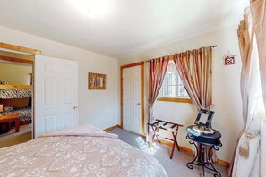 Ein Schlafzimmer mit einem Bett, einem Kleiderschrank, einem Spiegel und einem Fenster mit Vorhängen.