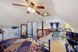 Ein Schlafzimmer mit Bett, Deckenventilator, Fernseher und Schreibtisch mit Stuhl.