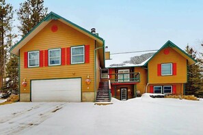Ein zweistöckiges Haus mit Garage, einer Treppe und einer verschneiten Auffahrt.
