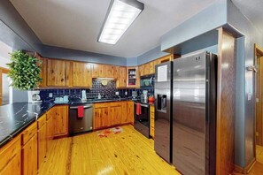 Eine Küche mit Holzausstattung, einem Edelstahlkühlschrank und einer schwarzen Arbeitsplatte.