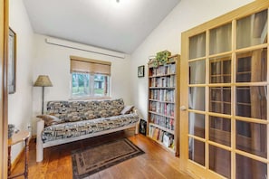 A cozy living room with a patterned sofa, a bookshelf, and a large wooden door.