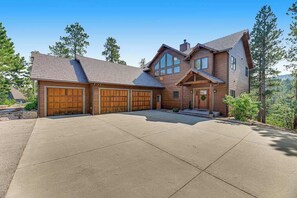 A two-story house with a large garage, a front porch, and a driveway. - Eagle Crest Nest - Secluded Cabin • Hot Tub & Decks (Spearfish)