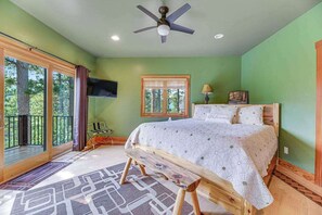 Une chambre à coucher avec un lit, un ventilateur de plafond, une fenêtre et une vue sur l’extérieur.