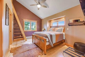 A bedroom with a sloped ceiling, a bed, a window, a wooden ladder, and a ceiling fan. - Eagle Crest Nest - Secluded Cabin • Hot Tub & Decks (Spearfish)