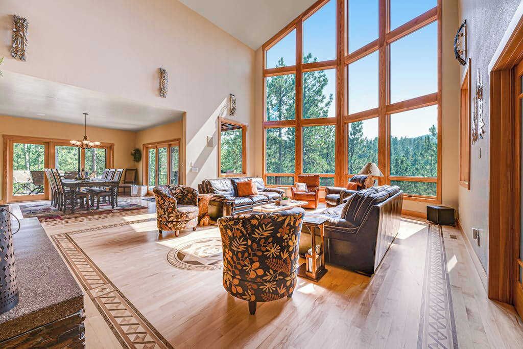 A spacious living room with a large window, a dining area, and a staircase.