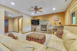 A living room with a fireplace, a ceiling fan, and a television. - Eagle Crest Nest - Secluded Cabin • Hot Tub & Decks (Spearfish)