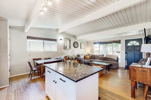 A spacious living area with a kitchen island, wooden flooring, and a dining table. - Goldfish Glen - Dog-Friendly Home • Pond & Mtn Views (Colorado Springs)