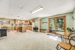 A spacious kitchen with wooden cabinets, a central island, and a dining area with a table and chairs. - Crooked Canyon Lodge - Secluded Lodge • Sauna & Hot Tub (Rapid City)
