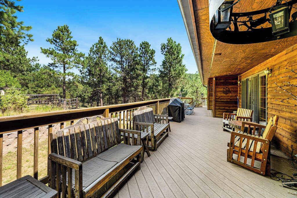 Une terrasse en bois avec des sièges d’extérieur et un barbecue.