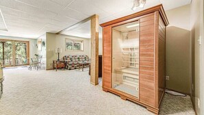 A spacious room with a large window, a wooden cabinet, and a carpeted floor. - Crooked Canyon Lodge - Secluded Lodge • Sauna & Hot Tub (Rapid City)