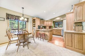 Une cuisine avec des meubles en bois, un coin repas avec des chaises et une grande fenêtre.