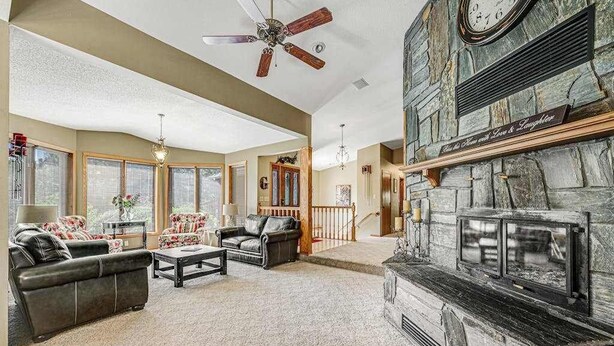 A spacious living room with a fireplace, leather sofas, and a ceiling fan. - Crooked Canyon Lodge - Secluded Lodge • Sauna & Hot Tub (Rapid City)