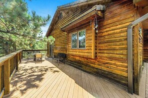 A wooden cabin with a deck, a table, and chairs. - Crooked Canyon Lodge - Secluded Lodge • Sauna & Hot Tub (Rapid City)