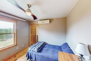 Ein Schlafzimmer mit Bett, Deckenventilator, Fenster und Klimaanlage.