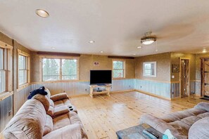 A spacious living room with a large flat-screen TV, two sofas, and a coffee table. - Hill City Haven • Black Hills Views & Deck (Hill City)