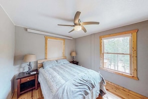 A bedroom with a bed, two bedside tables, a ceiling fan, and a window. - Hill City Haven • Black Hills Views & Deck (Hill City)