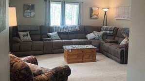 Een woonkamer met een hoekbank, een houten salontafel en een fauteuil met een patroon.