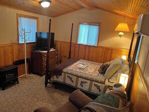 A cozy bedroom with a bed, dresser, television, and a heater. - Mountain Escape - Mountain-View Home + Cabin w/ Deck (Sturgis)