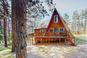 A cabin with a wooden deck, multiple windows, and a staircase leading to the entrance. - Mountain Escape - Mountain-View Home + Cabin w/ Deck (Sturgis)