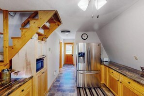 A kitchen with wooden cabinets, a stainless steel refrigerator, and a wooden staircase. - Mountain Escape - Mountain-View Home + Cabin w/ Deck (Sturgis)