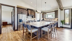 Una cocina amplia con una isla grande, piso de madera y electrodomésticos modernos.