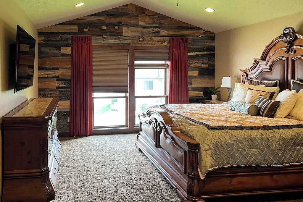 Une chambre à coucher avec un grand lit, une commode, un téléviseur et un mur en pierre.