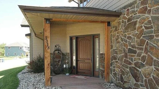 Una casa con fachada de piedra, puerta principal de madera y el número 308 en el poste.