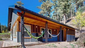 A cabin with a wooden exterior, large windows, and a covered porch area. - Honey Bee Hideaway - Dog-Friendly Home - Porch & Mtn Views (Lead)