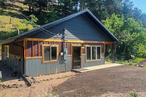A small cabin with a sloped roof, large windows, and a door leading to the interior. - Honey Bee Hideaway- Dog-Friendly Home - Porch & Mtn Views (Lead)