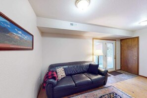 A living room with a black leather sofa, a rug, and a framed picture on the wall. - Horseshoe Haven - Mountain-View Home • Deck & Grill (Divide)