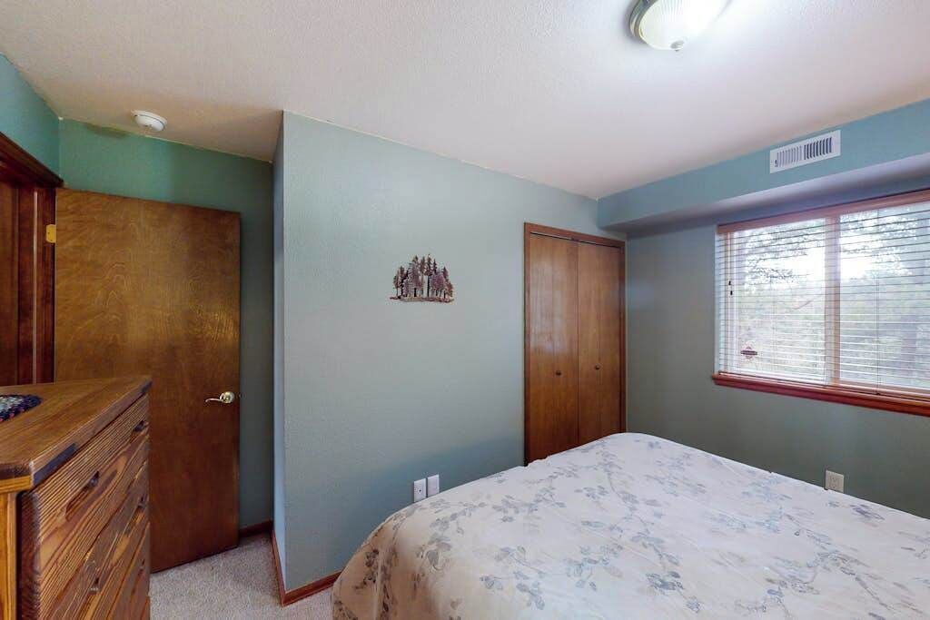 Un dormitorio con una cama, cómoda y dos puertas.