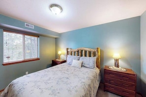 A bedroom with a bed, two bedside tables with lamps, a window with blinds, and a ceiling light. - Horseshoe Haven - Mountain-View Home • Deck & Grill (Divide)