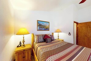 A bedroom with a bed, two bedside tables with lamps, a wooden wardrobe, and a framed picture on the wall. - Horseshoe Haven - Mountain-View Home • Deck & Grill (Divide)