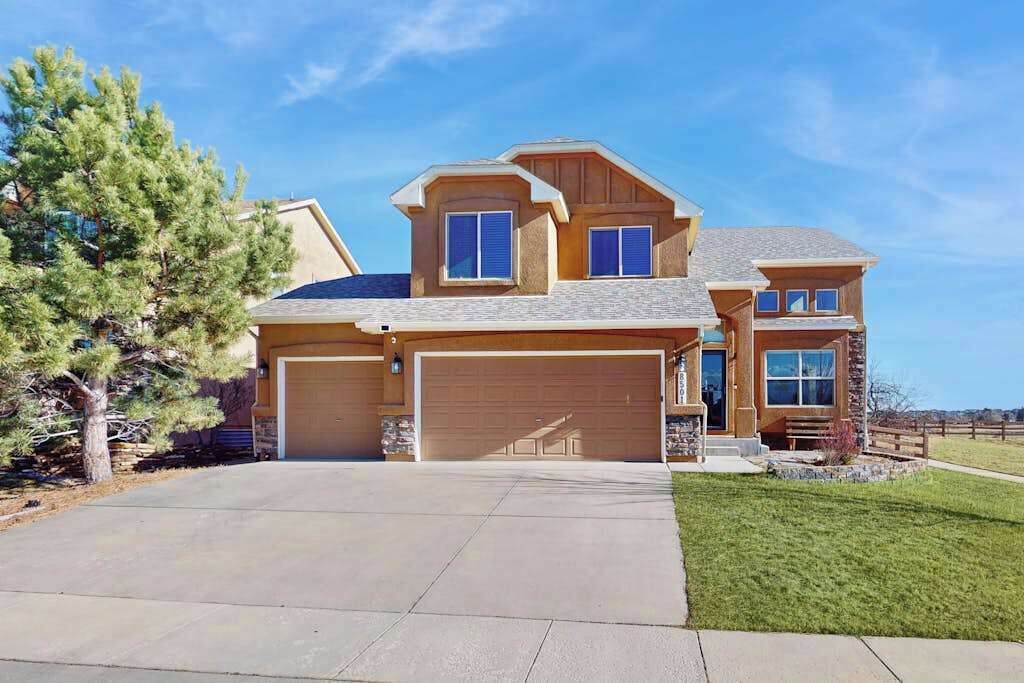 A two-story house with a garage, a covered driveway, and a stone exterior.