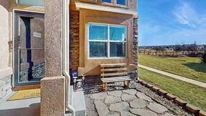 A two-story house with a stone facade, a front door, a bench, and a paved driveway. - Jack’s Ranch House- Family Home • Game Room & Mtn Views (Colorado Springs)