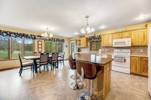 A kitchen with a bar area, wooden cabinets, a white stove, and a dining table with chairs.