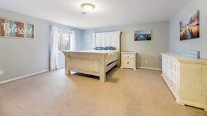 Ein Schlafzimmer mit Bett, Nachttisch, Schminktisch und Kunstwerken an den Wänden.